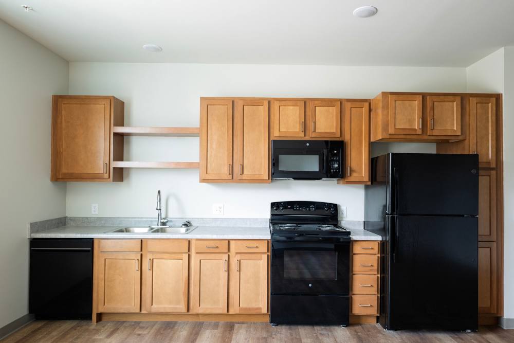 Kitchen with wood cabinets, black appliances, and countertop at Monarch Station in Louisville, Kentucky