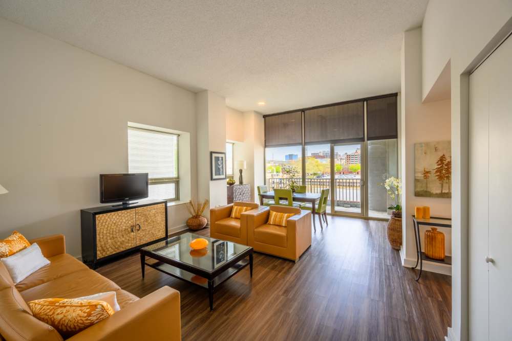 Living room with wood-style flooring and balcony at The Residences at Christina Landing in Wilmington, Delaware