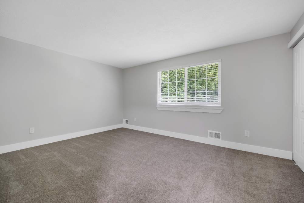 Spacious carpeted bedroom with natural light at Valley Brook Townhomes in Rochester, New York
