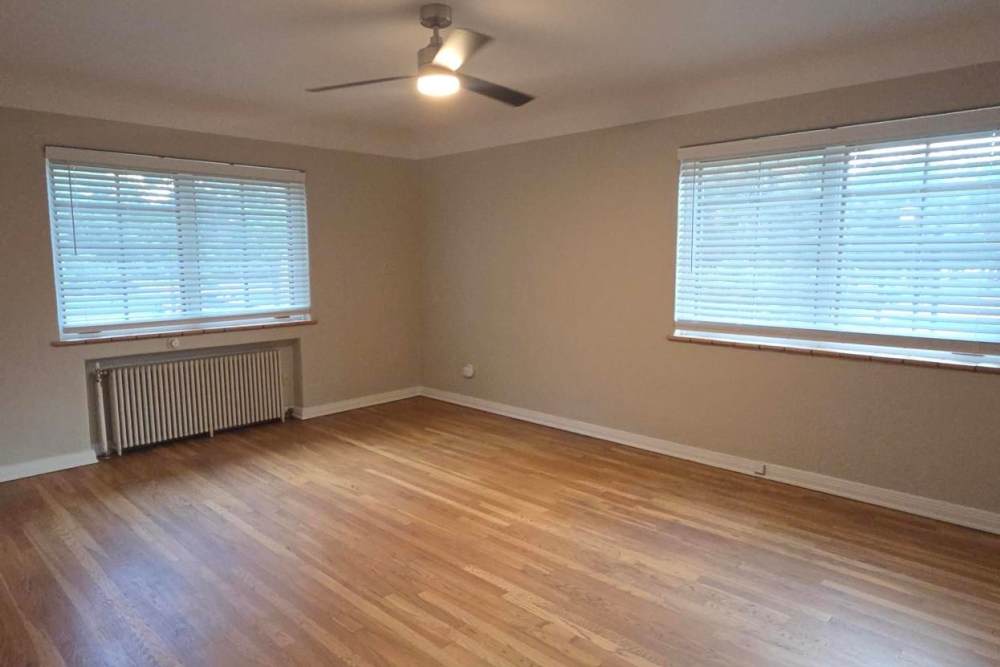 Living room with hardwood floors, two windows, blinds, ceiling fan and radiator beneath window Cascade Park in Colorado Springs, Colorado