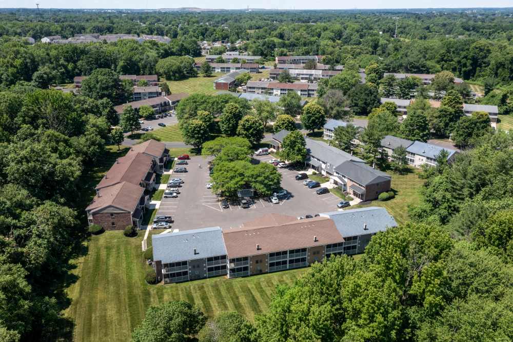 Aerial view of apartment community with buildings, parking, and green surroundings at Kuser Village in Hamilton, New Jersey