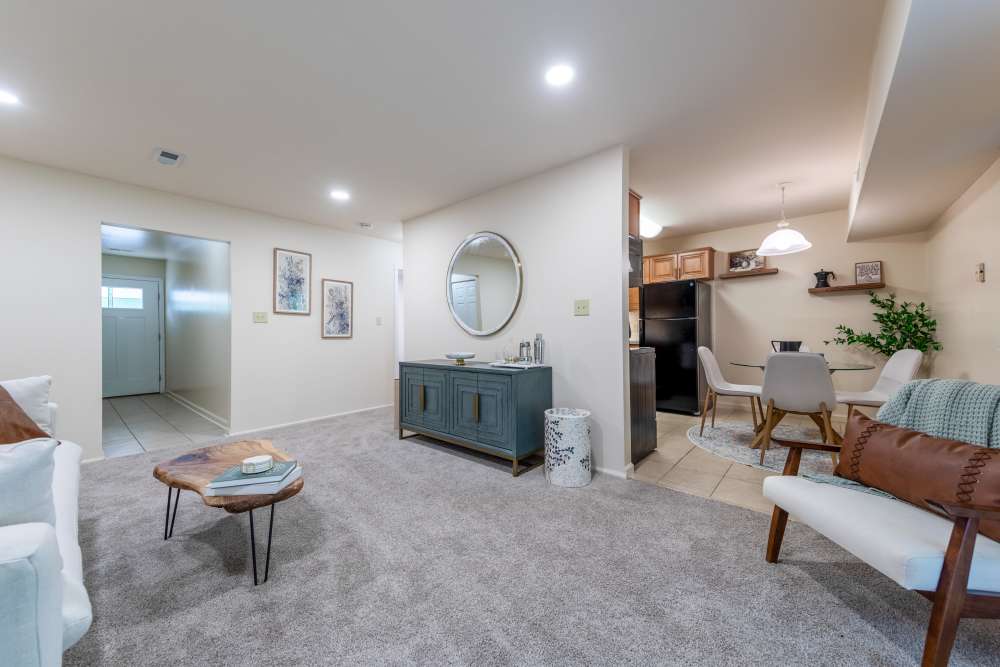 Bright living space with TV stand, wall art, and adjacent dining area at Kuser Village in Hamilton, New Jersey