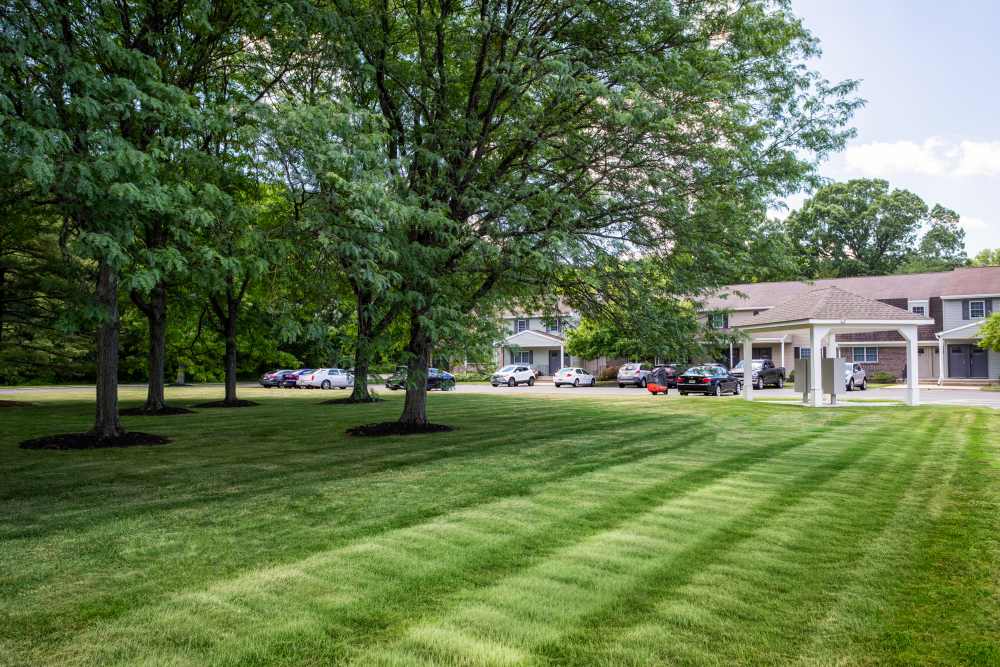 Tree-lined lawn and parking area with covered entrance at Kuser Village in Hamilton, New Jersey