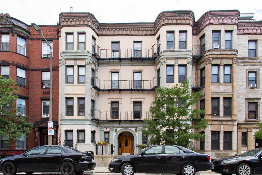 Exterior view of the building with parking cars at 71 Westland Apartments in Boston, Massachusetts