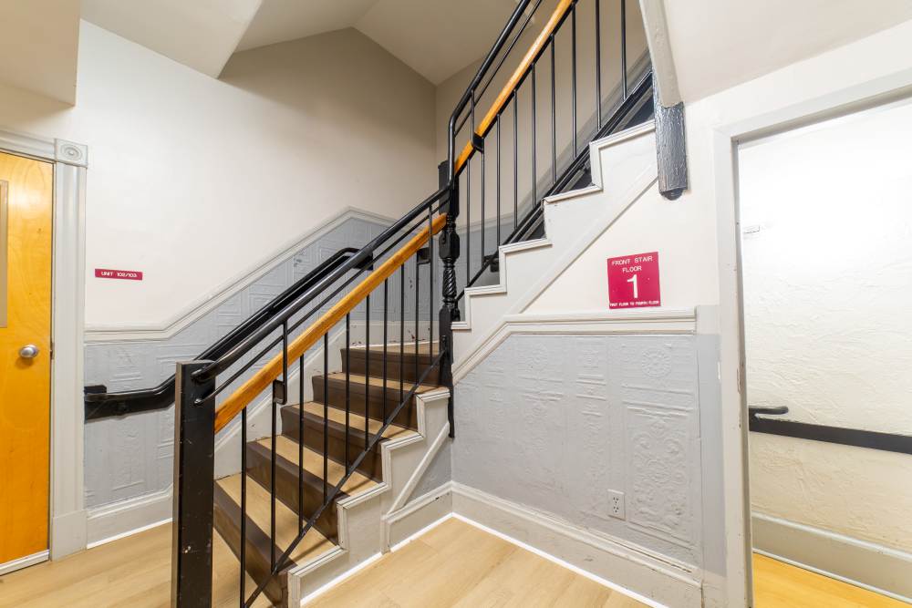 Indoor stairwell with brown steps, black railing access to upper level at 71 Westland Apartments in Boston, Massachusetts