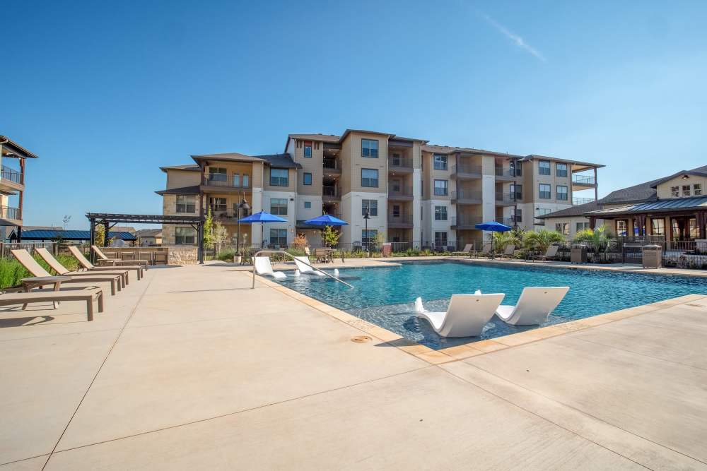 outdoor pool with seating and view of Cypress Creek at Stoney Ridge apartments