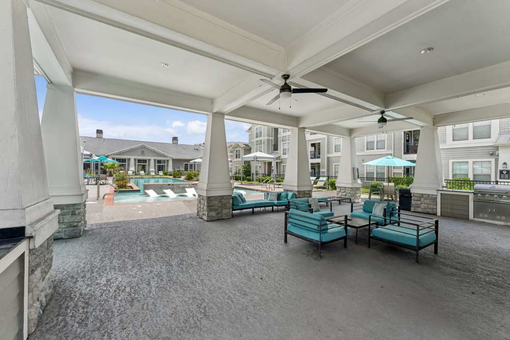 Covered lounge area with ceiling fans and turquoise seating at Aria Victoria Apartments in Victoria, Texas