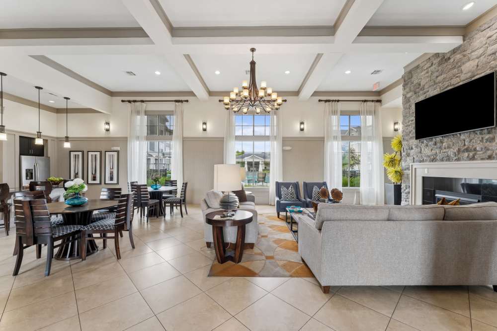 Bright clubhouse living area with wood-style flooring, modern artwork, and stylish patterned chairs at Aria Victoria Apartments in Victoria, Texas