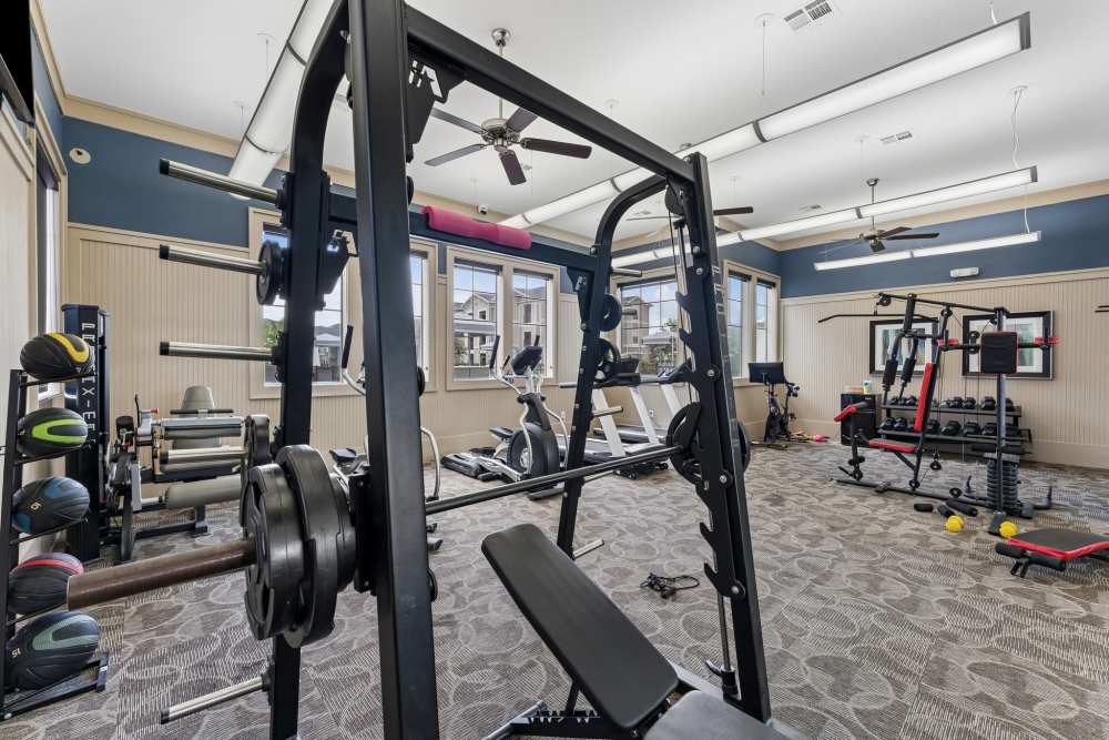 Well-equipped fitness center with cardio machines, weight equipment, and large mirrors at Aria Victoria Apartments in Victoria, Texas
