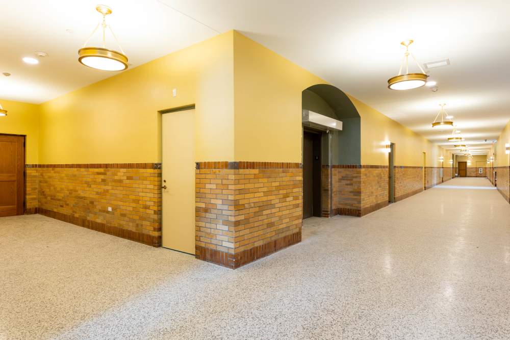 Spacious hallway with vintage brick accents at Elias Brookings Apartments in Springfield, Massachusetts