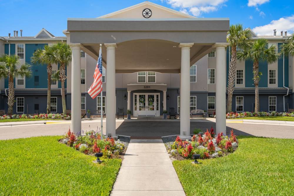 Senior living community entrance with covered portico and gardens at Gentry Park Orlando in Orlando, Florida