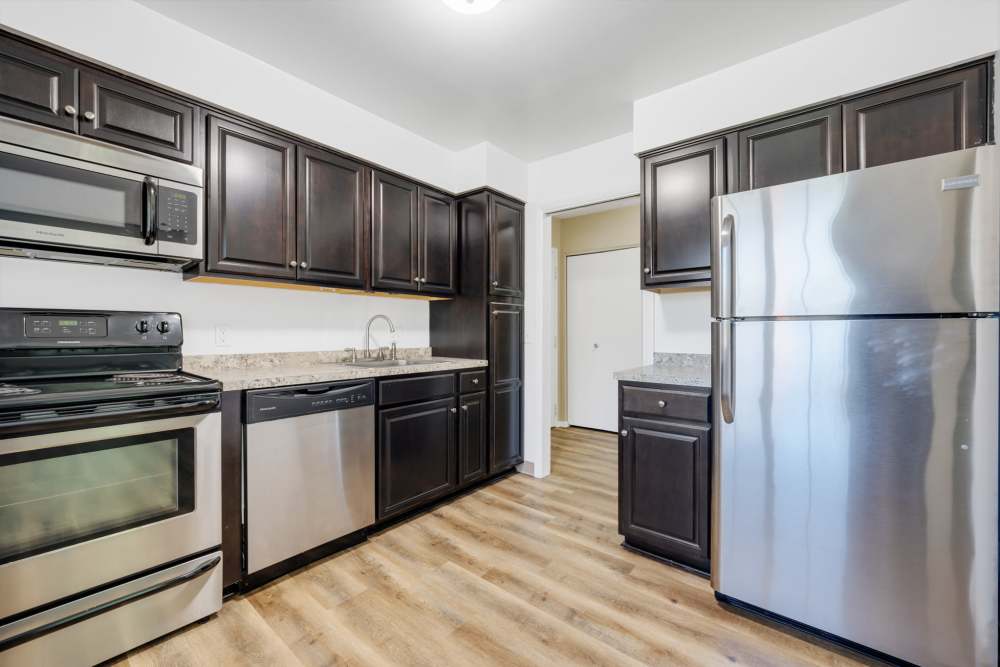 Modern kitchen with stainless steel appliances and wood flooring at Pittsford Village Estates in Pittsford, New York
