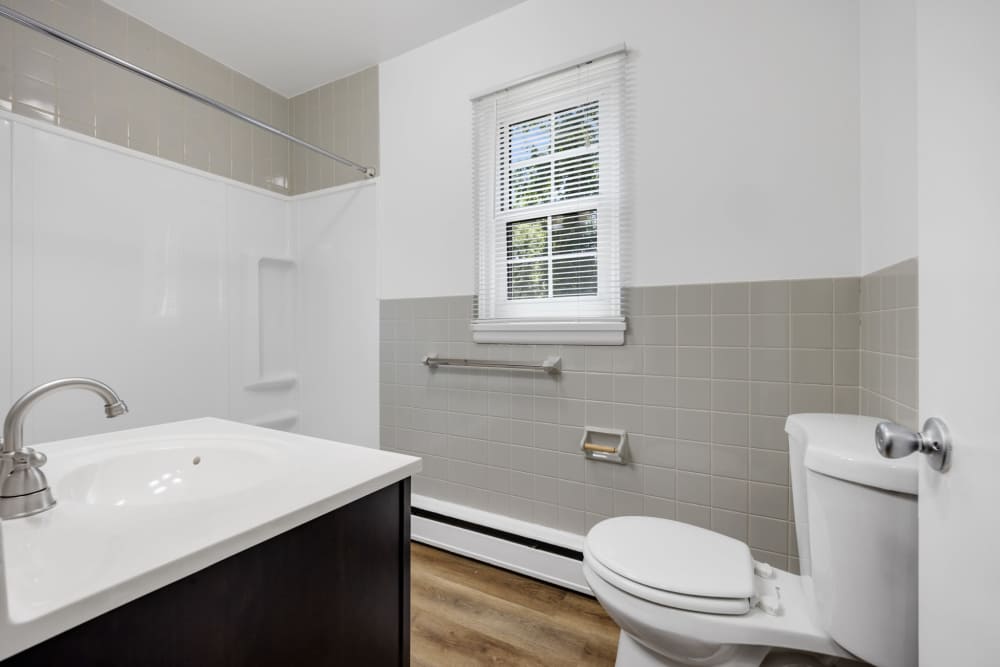 Full bathroom with bathtub, vanity, and toilet in neutral tones at Pittsford Village Estates in Pittsford, New York