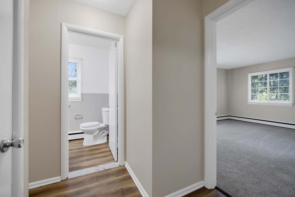 Bathroom entry leading to carpeted bedroom with neutral walls at Pittsford Village Estates in Pittsford, New York