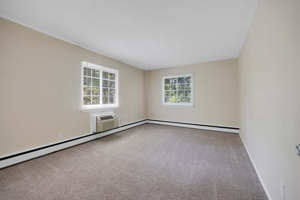 Empty carpeted bedroom with windows and light gray walls at Pittsford Village Estates in Pittsford, New York