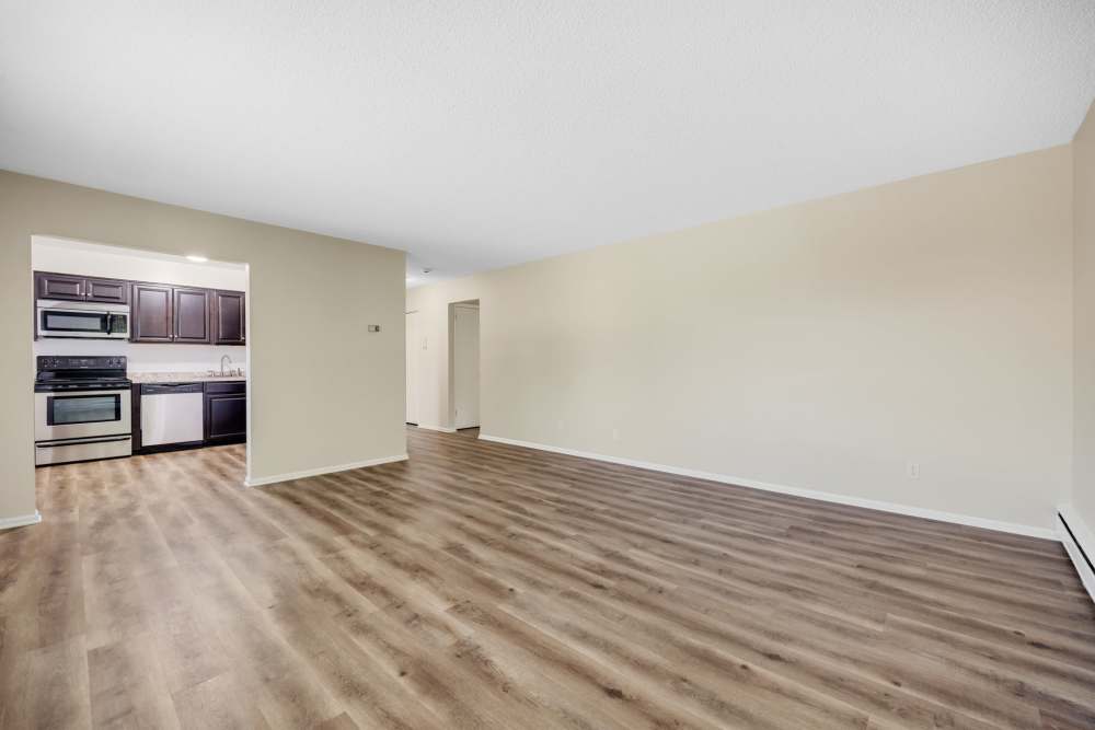 Wide living area with wood-style floors and kitchen access at Pittsford Village Estates in Pittsford, New York
