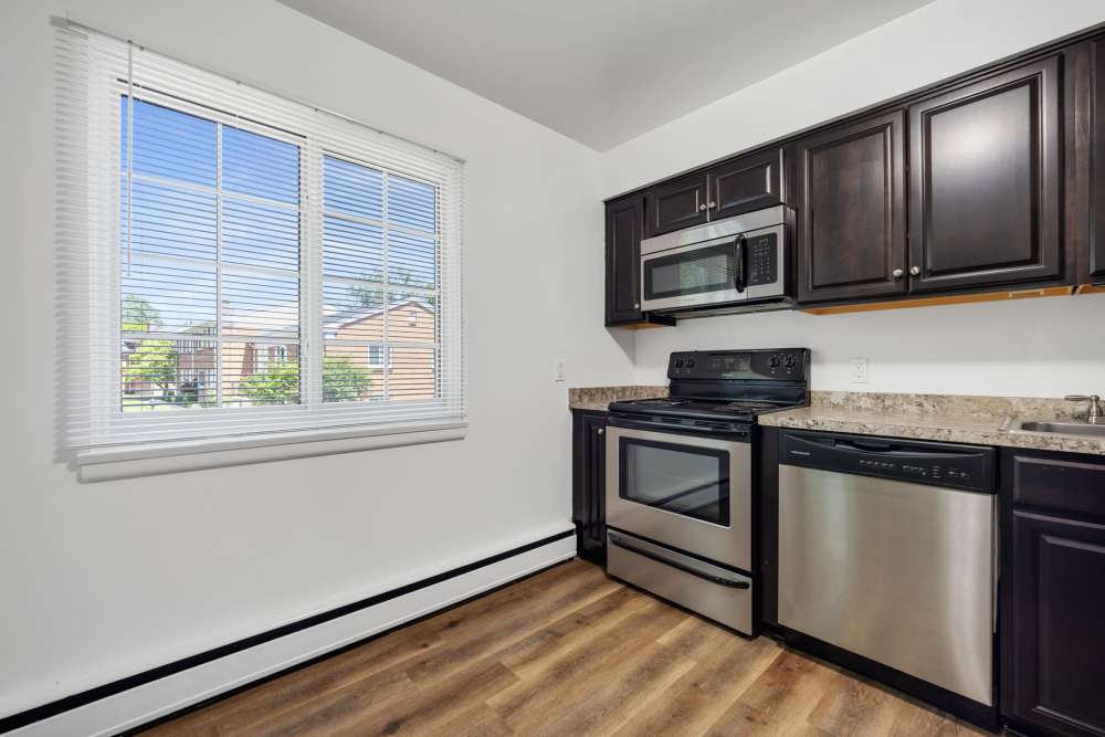 Kitchen with large window, dark cabinetry, and natural light at Pittsford Village Estates in Pittsford, New York