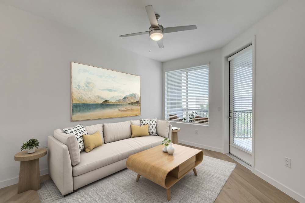Bright living room with a sofa, wood coffee table, and large window near balcony at Heirloom at Bruner in Las Vegas, Nevada