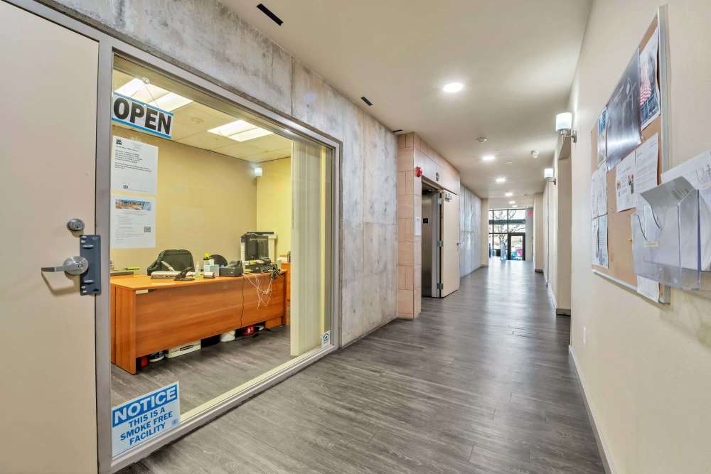 Apartment community lobby with reception desk, stylish interior finishes, and spacious corridor at North Main Village in Milwaukie, Oregon  