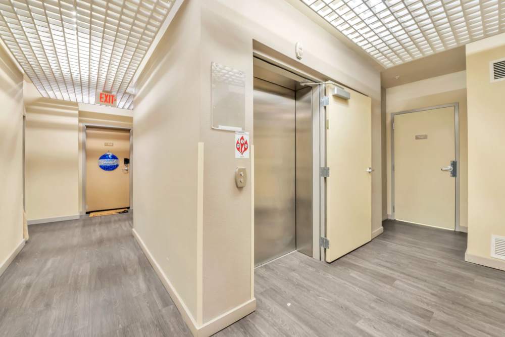 Modern apartment hallway with light wood flooring, contemporary finishes, and elevator access at North Main Village in Milwaukie, Oregon  