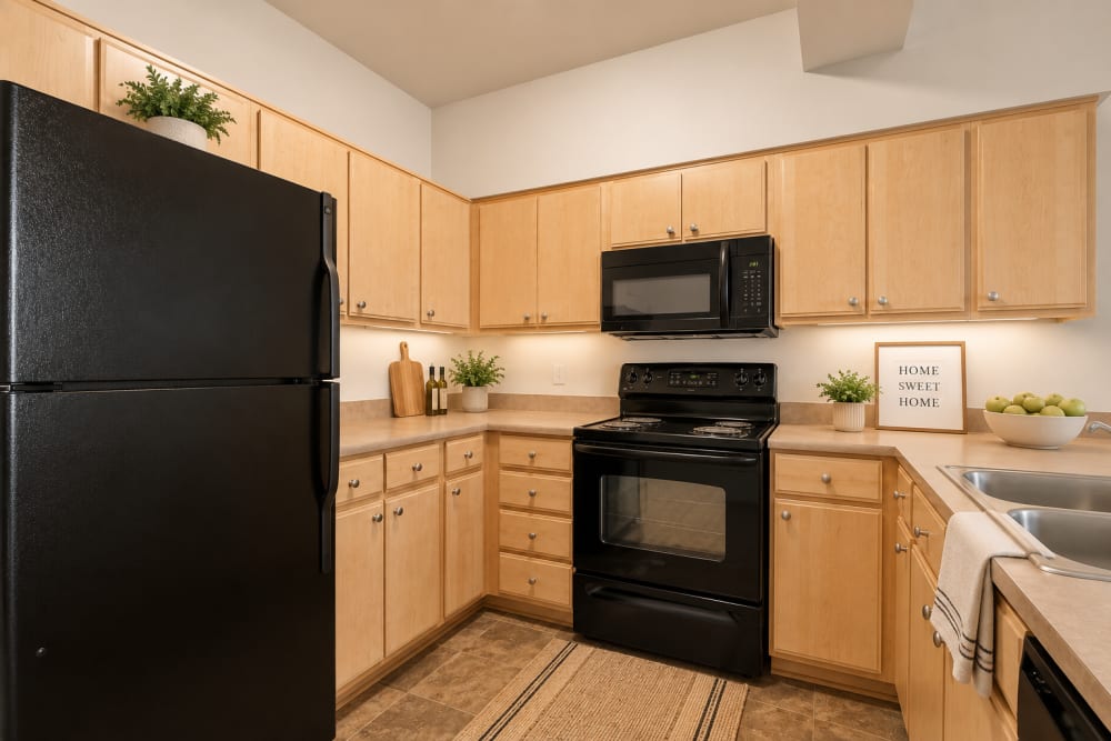 Modern kitchen featuring black refrigerator, black stove, wood cabinets, and ample countertop space at North Main Village in Milwaukie, Oregon  