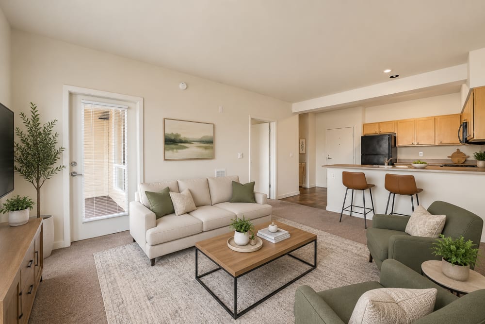 Open-concept living room and kitchen featuring contemporary furnishings, natural light, and wood-tone cabinetry at North Main Village in Milwaukie, Oregon  