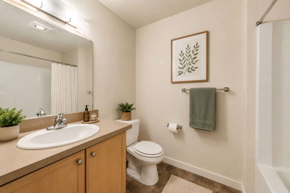 Modern bathroom vanity with wood cabinetry, large mirror, and stylish fixtures at North Main Village in Milwaukie, Oregon  