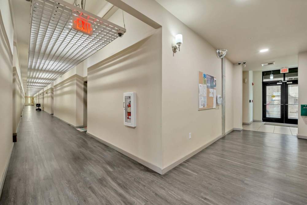 Bright apartment hallway with modern flooring, neutral walls, and natural light from entry doors at North Main Village in Milwaukie, Oregon  