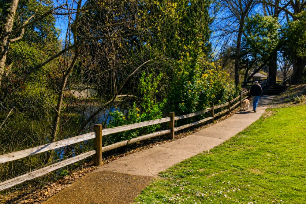 Scenic walking path bordered by a wooden fence and lush greenery in a landscaped community setting at North Main Village in Milwaukie, Oregon  
