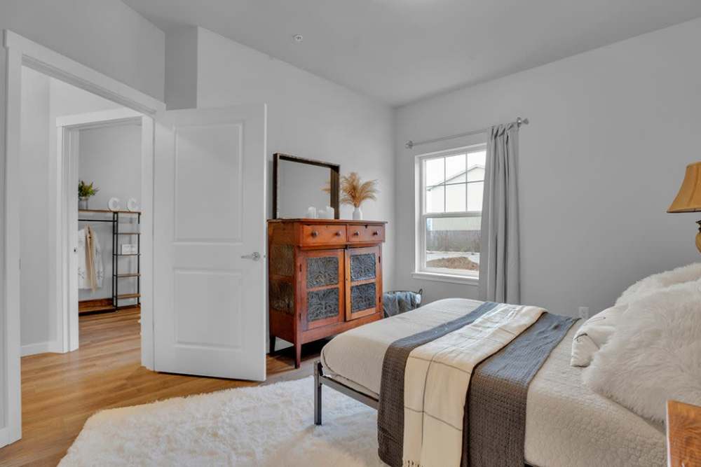 Spacious bedroom with dresser, natural light, and adjacent room access, at Cleveland Crossings in Woodburn, Oregon