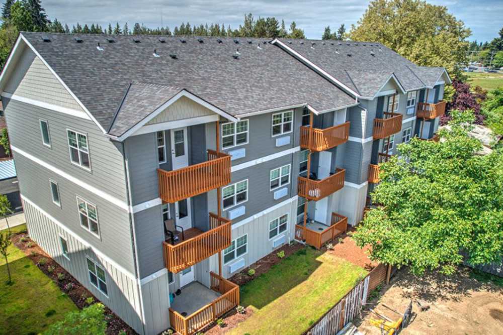 Three-story apartment building with private balconies surrounded by trees, Cleveland Crossings in Woodburn, Oregon