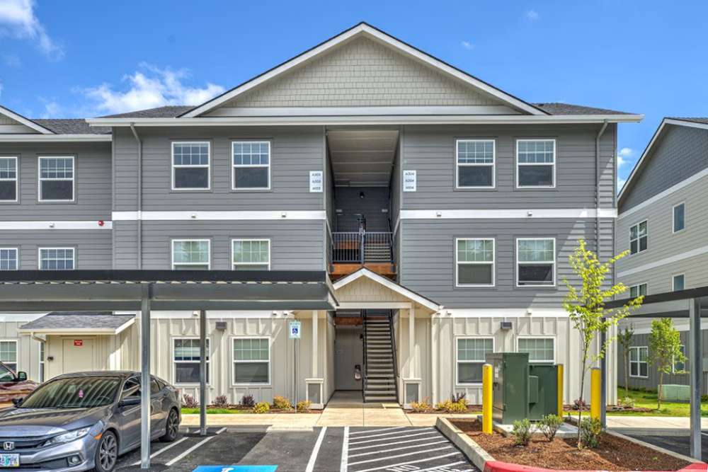 Front elevation of apartment building with central entrance and parking, Cleveland Crossings in Woodburn, Oregon