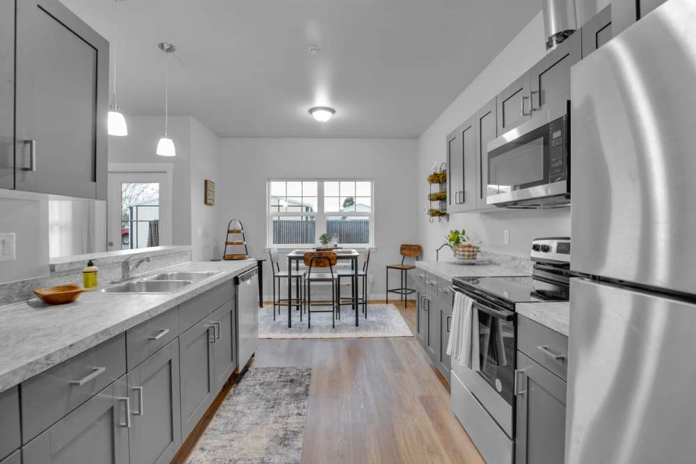 Spacious kitchen with quartz-style countertops and stainless steel refrigerator, at Cleveland Crossings in Woodburn, Oregon