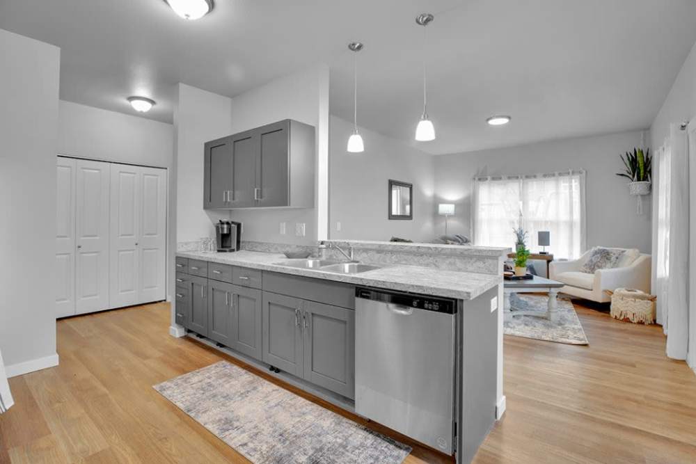 Open-concept kitchen with large island, dishwasher, and adjacent living space, at Cleveland Crossings in Woodburn, Oregon