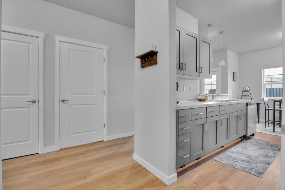 Apartment entry hallway with wood-style flooring and view into the kitchen, at Cleveland Crossings in Woodburn, Oregon