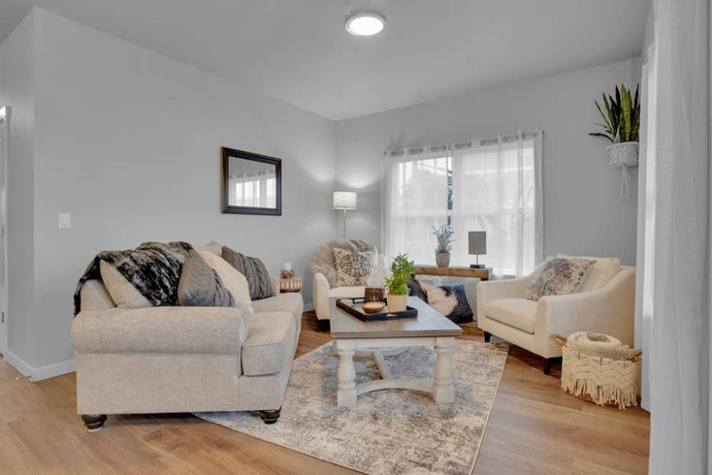 Comfortable living room with plush seating, coffee table, and large window, at Cleveland Crossings in Woodburn, Oregon