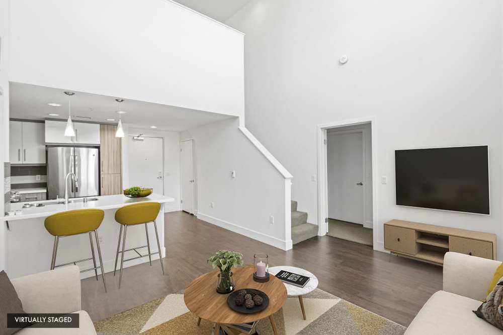 Virtually staged living room with vaulted ceilings, breakfast bar, and contemporary finishes at The Marke Apartment Homes in Santa Ana, California