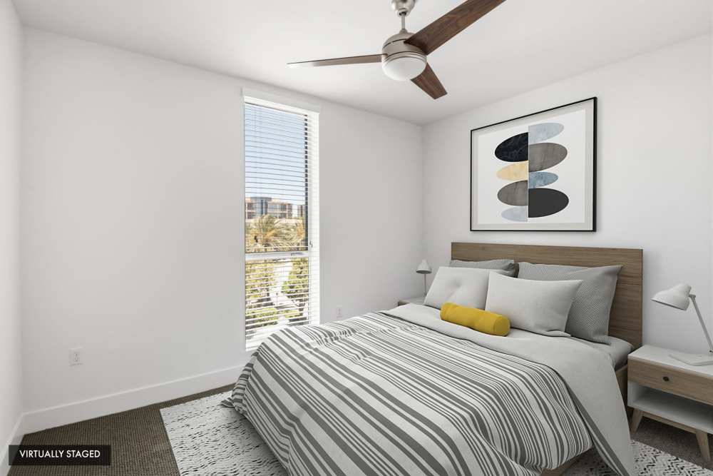 Virtually staged bedroom with large window, ceiling fan, and contemporary decor at The Marke Apartment Homes in Santa Ana, California