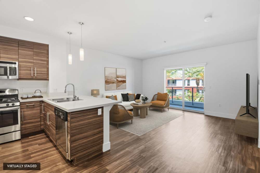 Virtually staged open-concept apartment featuring modern kitchen, living room, and private balcony at The Marke Apartment Homes in Santa Ana, California