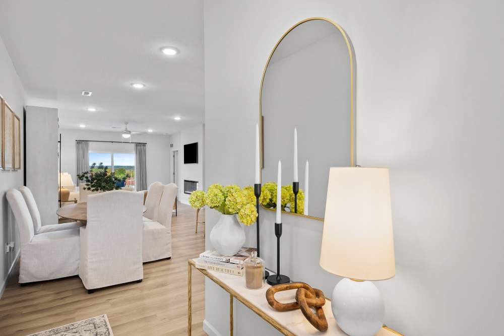 A modern living room with a white sofa set, a coffee table with a lamp, and a vase of yellow flowers.