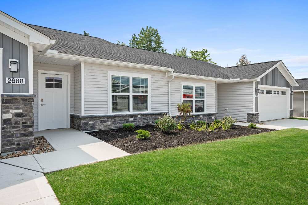 Single-story townhome with attached garage, stone accents, and landscaped entrance at Villas at Mulberry Way in Kalamazoo, Michigan