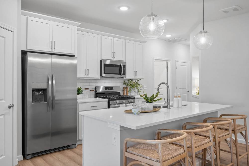 White kitchen with island, barstools, and steel appliances at Villas at Mulberry Way in Kalamazoo, Michigan
