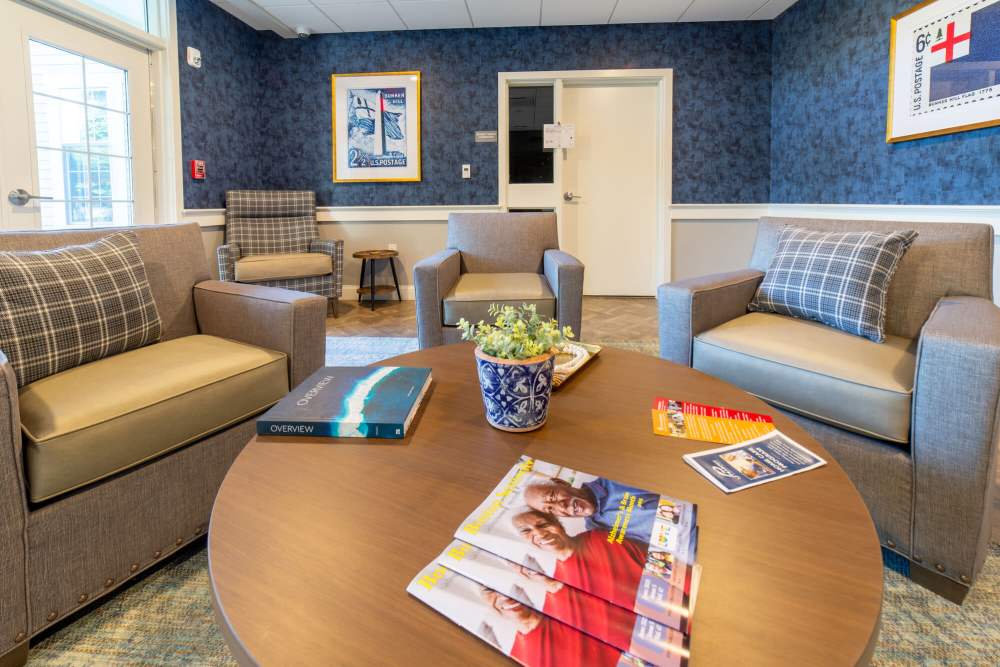 Cozy lounge area with a coffee table displaying brochures and a plant at The Charlestown in Charlestown, Massachusetts