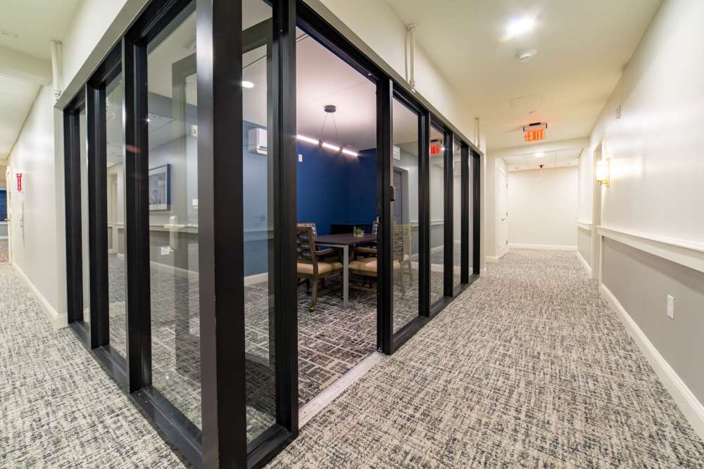 Modern hallway leading to glass-walled meeting room with stylish seating at The Charlestown in Charlestown, Massachusetts