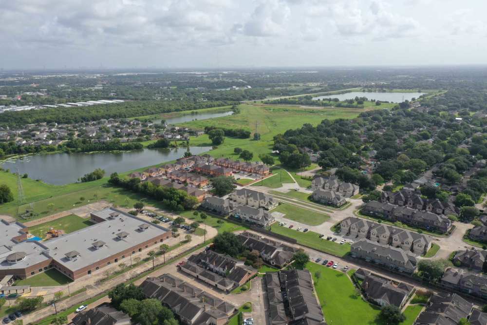 Aerial view of residential buildings and lakes at 36 Palms Townhomes in Missouri City, Texas