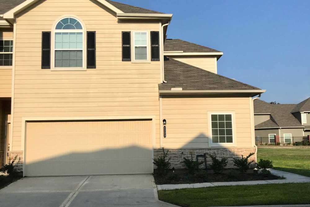 Tan exterior with black shutters and garage door at 36 Palms Townhomes in Missouri City, Texas