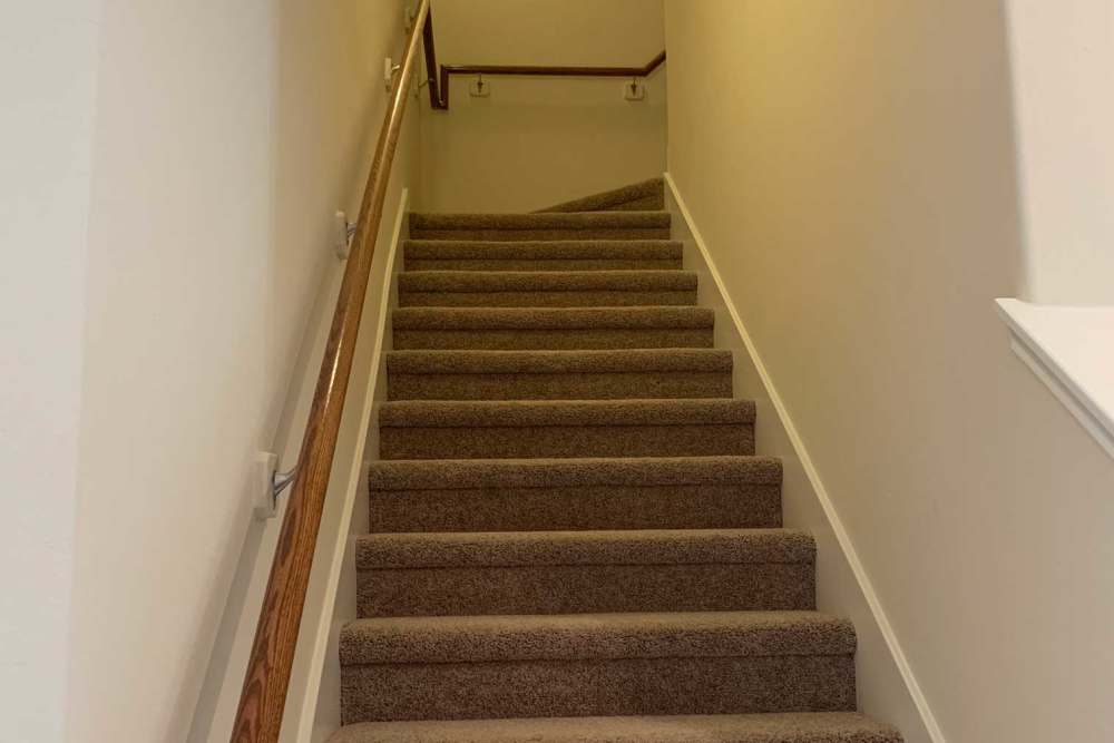 Carpeted stairs with wooden handrail at 36 Palms Townhomes in Missouri City, Texas