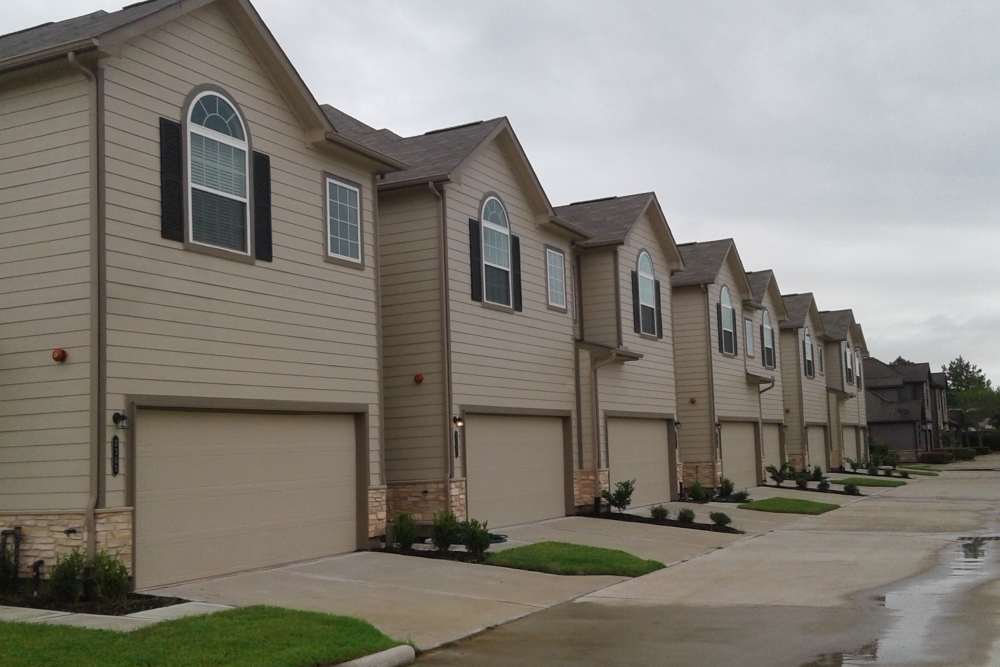 Row of beige houses with garages at 36 Palms Townhomes in Missouri City, Texas