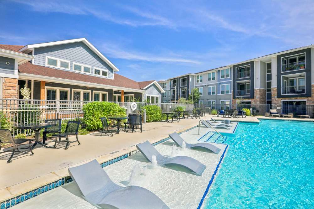 Resort-style pool with sun loungers and apartment clubhouse Limestone Ridge Apartments in Austin, Texas