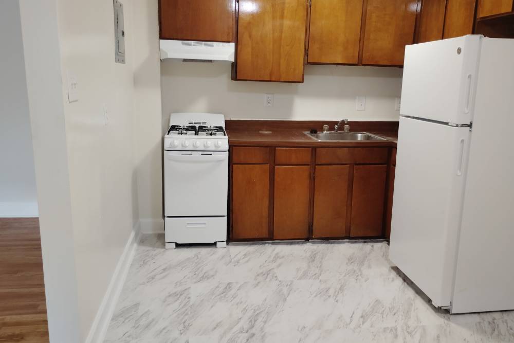 Kitchen with white appliances and wooden cabinetry at Franklin Apartments in Takoma Park, Maryland